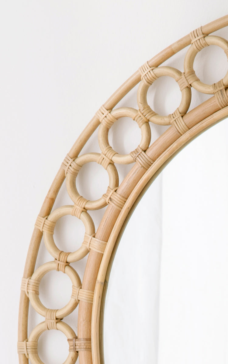 This is a close-up image of Mira Mirror in natural rattan. Detail of the circular rattan ring border framing the round mirror.