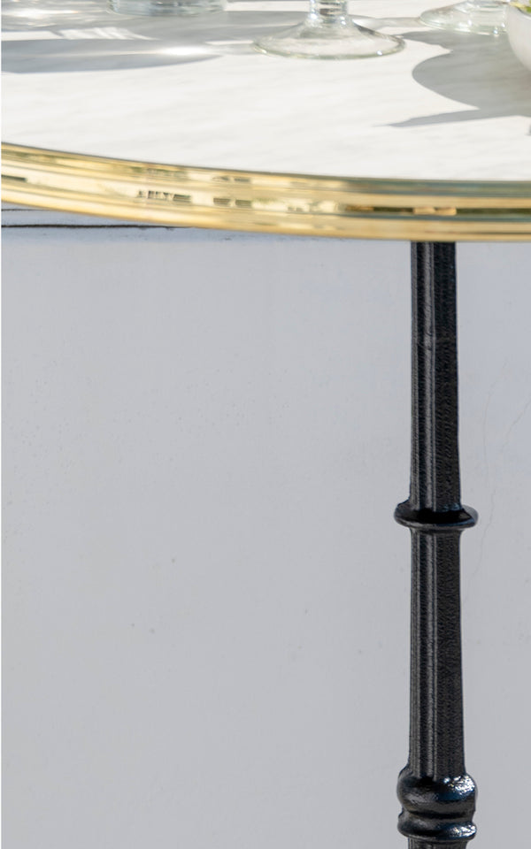 This is a close-up image of Lyon Bar Table Versalite Marble Ø70 cm in cast iron. Marble top and detailed cast iron column with turned profile.