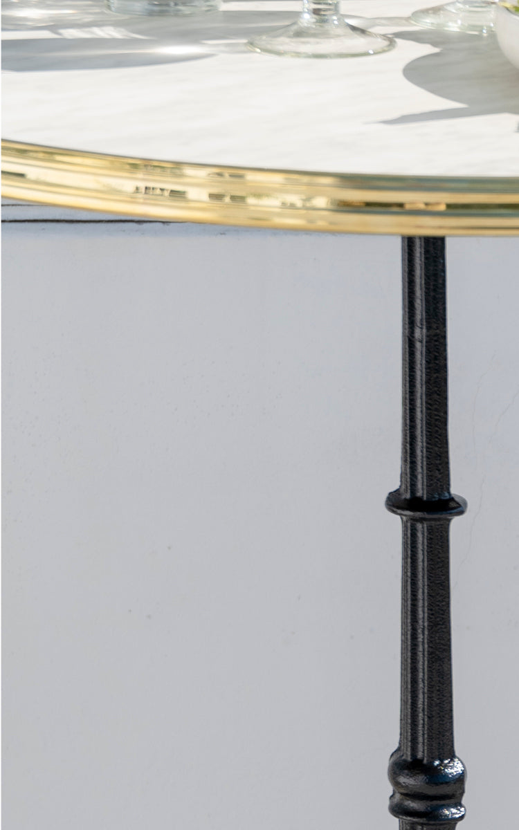 This is a close-up image of Lyon Bar Table Versalite Marble Ø70 cm in cast iron. Marble top and detailed cast iron column with turned profile.