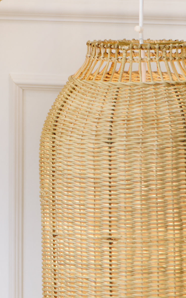 This is a close-up image of Kou Lampshade in natural core weave rattan frame. The tightly woven lantern shape and warm glow are highlighted.