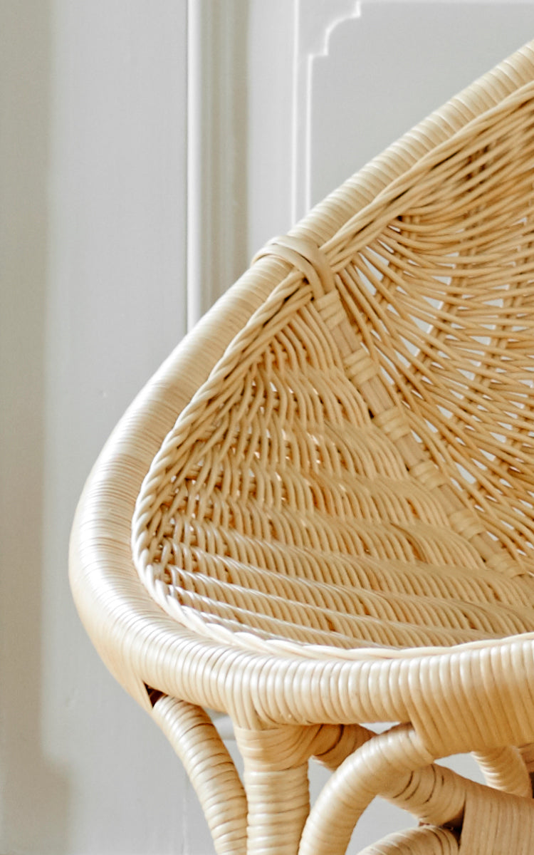 This is a close-up image of Rana Lounge Chair in natural core weave rattan frame. Detail of the woven shell seat and curved rattan frame edge.