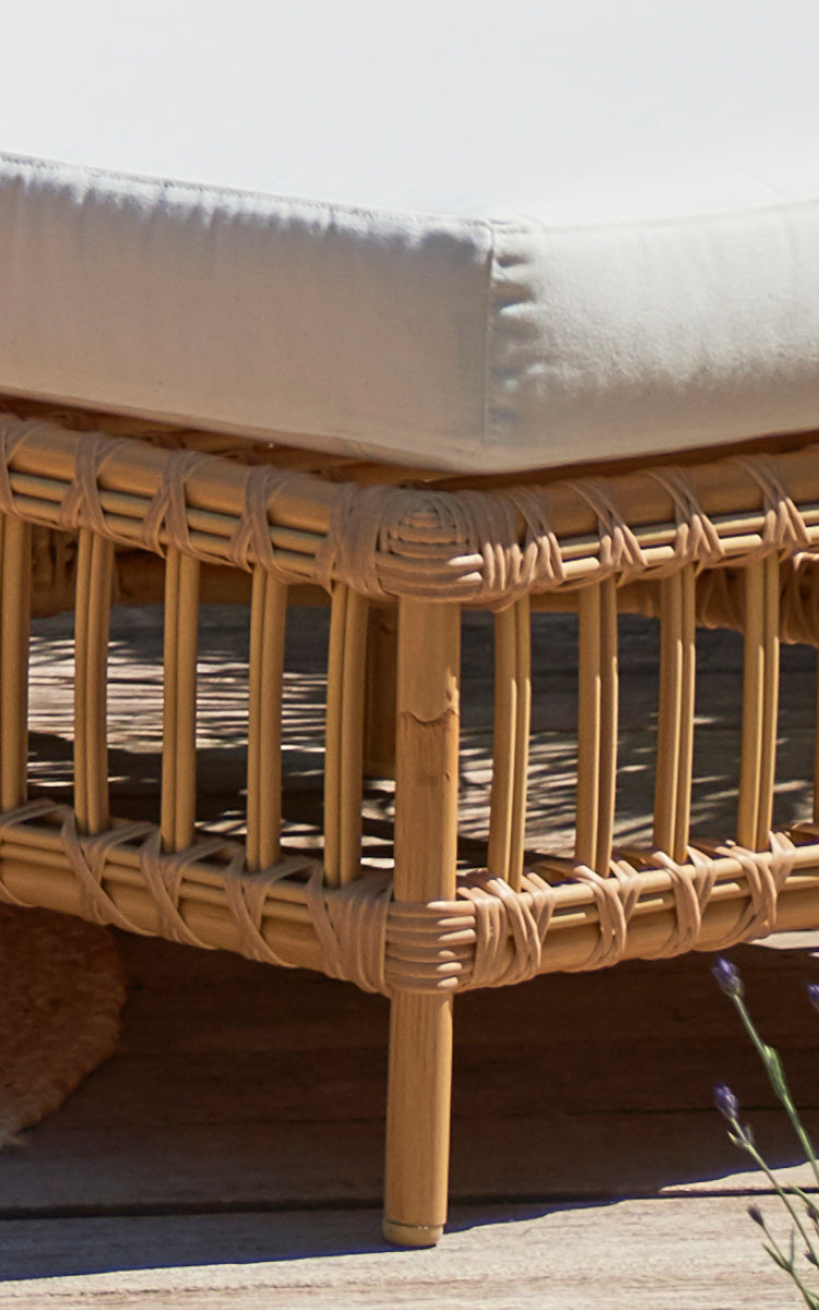 This is a close-up image of Maggie Sofa Pouf Module w. Glass in natural aluminium artfibre. Cushion on rattan frame with wrapped slat detail.