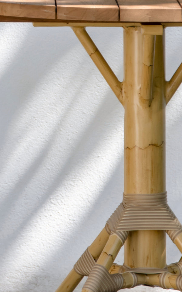 This is a close-up image of Nicole Cáfe Table | Teak Ø80 cm in natural aluminium artfibre. Detail of the woven texture and frame construction.