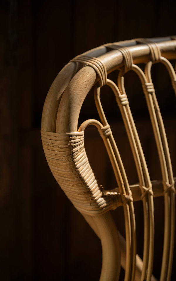 This is a close-up image of Fox Lounge Chair in polished natural rattan. Looped backrest and wrapped rattan joints.
