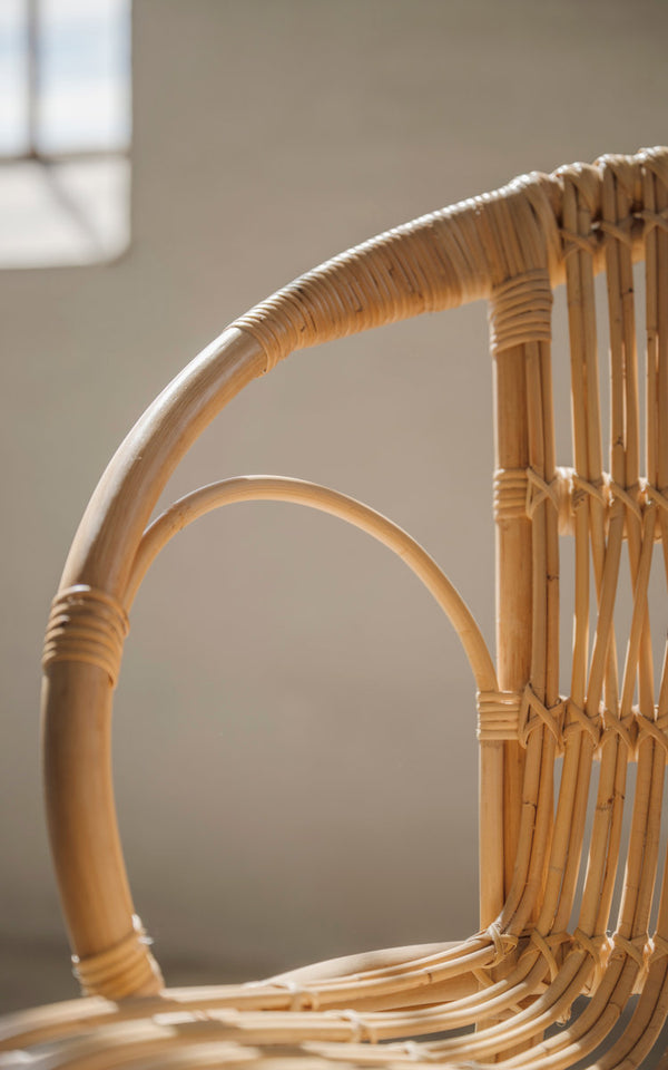 This is a close-up image of Robert Dining Chair in polished natural rattan. Curved armrest and wrapped rattan details.