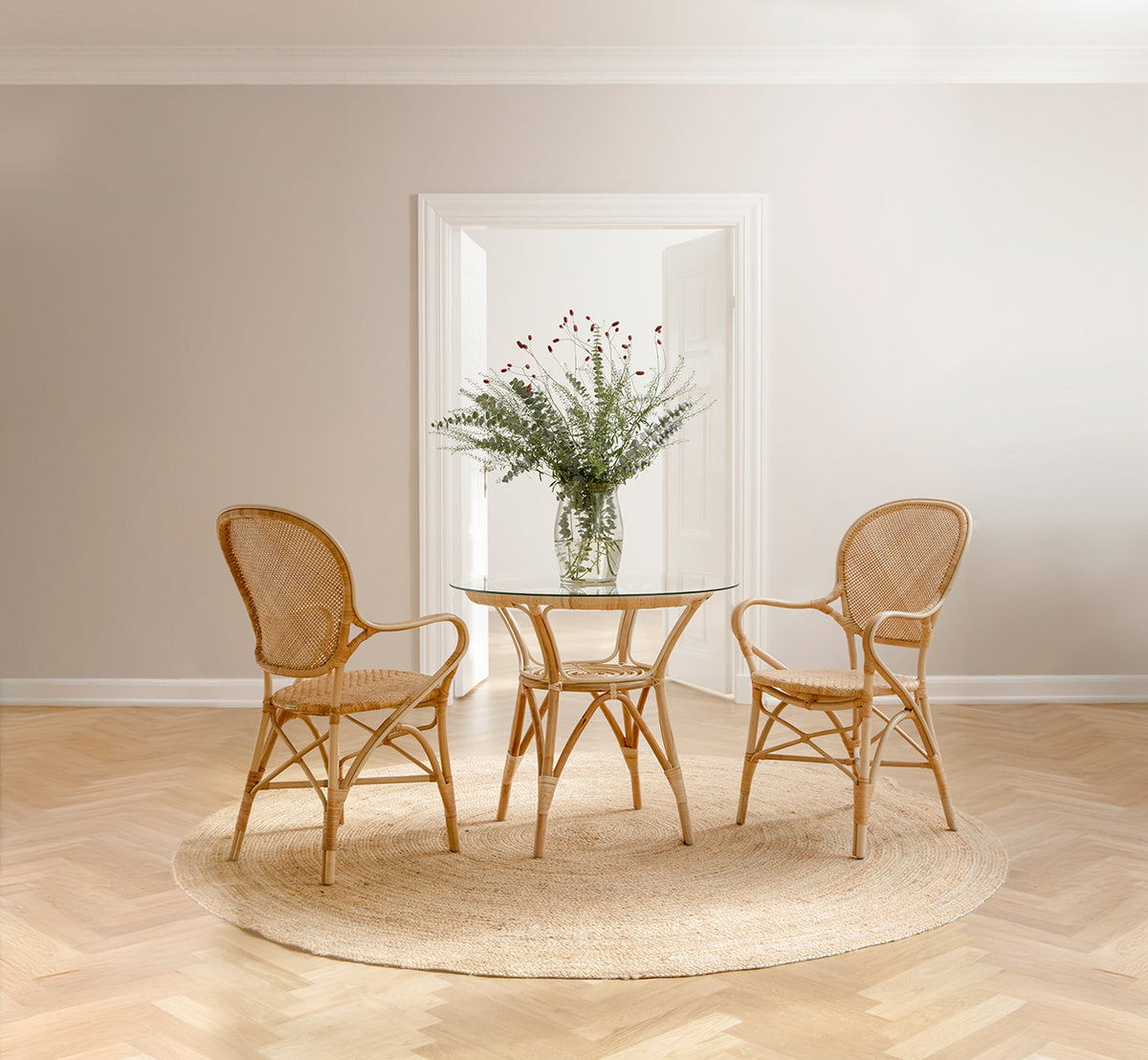 This is a lifestyle image of Rossini Dining Armchair in natural rattan. Styled in a bright interior setting.