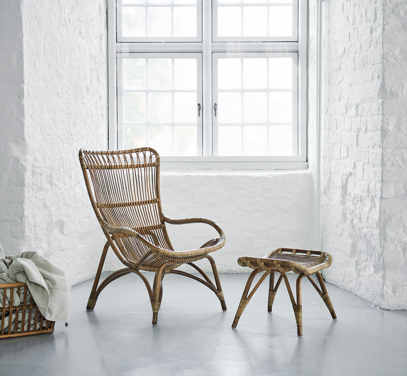 This is a lifestyle image of Monet Lounge Chair in antique rattan. In a butterfly wallpaper room with decorative Moroccan lanterns.