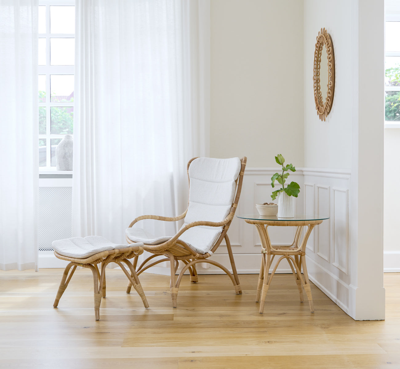 This is a lifestyle image of Monet Lounge Chair in natural rattan. In a blush-walled room with herringbone floor and rattan trolley.