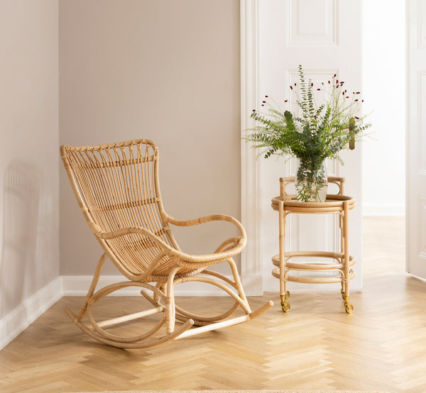 This is a lifestyle image of Romeo Trolley in natural rattan. Styled with glasses in a cozy corner with herringbone parquet floor.
