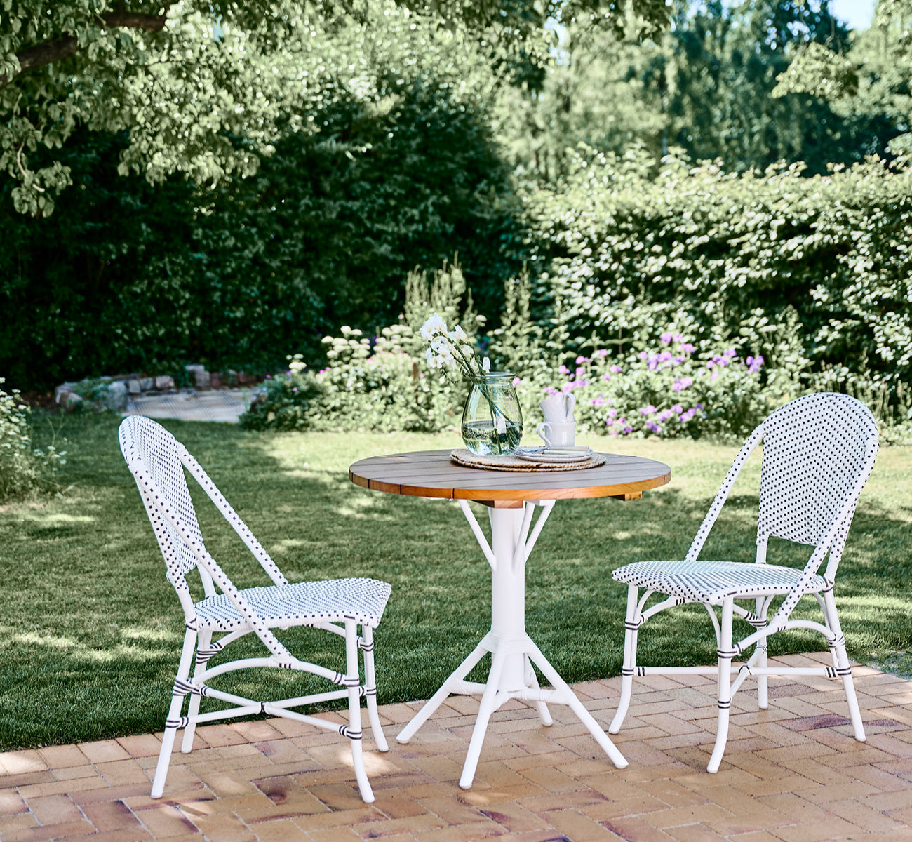 This is a lifestyle image of Sofie Exterior Dining Chair in white aluminium frame white w cappuccino dot artfibre.