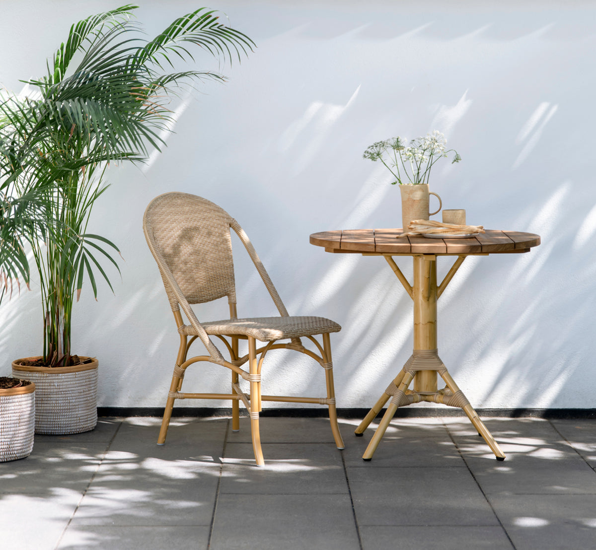 This is a lifestyle image of Sofie Exterior Dining Chair in almond aluminium frame natural ArtFibre. On a Mediterranean terrace.