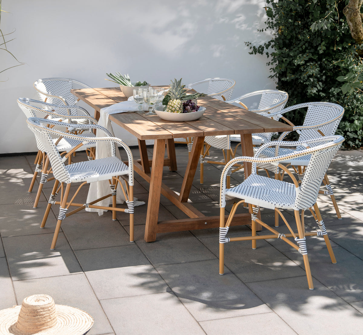 This is a lifestyle image of Madeleine Exterior Dining Chair in almond aluminium frame white w cappuccino dot ArtFibre. Garden dining with teak table.