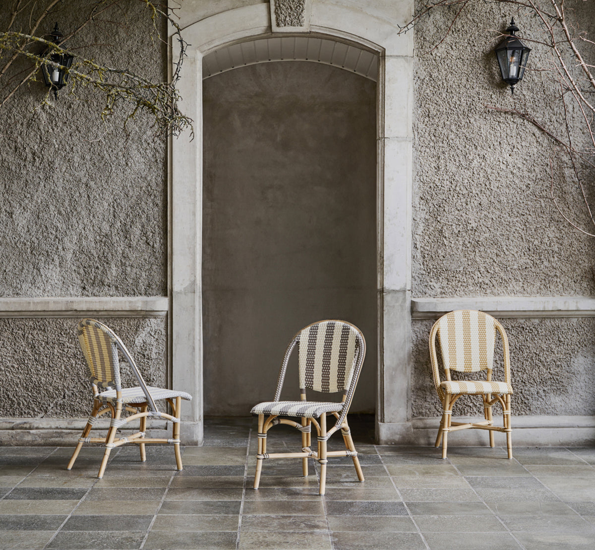 This is a lifestyle image of Sofie Dining Chair in striped cappuccino ivory artfibre skin on rattan frame. Styled in a bright interior setting.