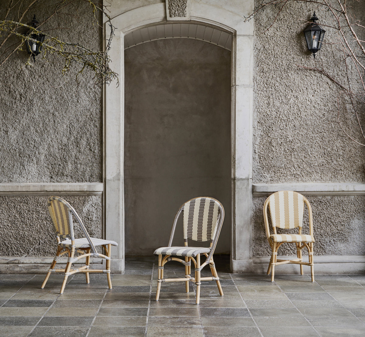 This is a lifestyle image of Sofie Dining Chair in striped grey ivory artfibre skin on rattan frame. Styled in a bright interior setting.