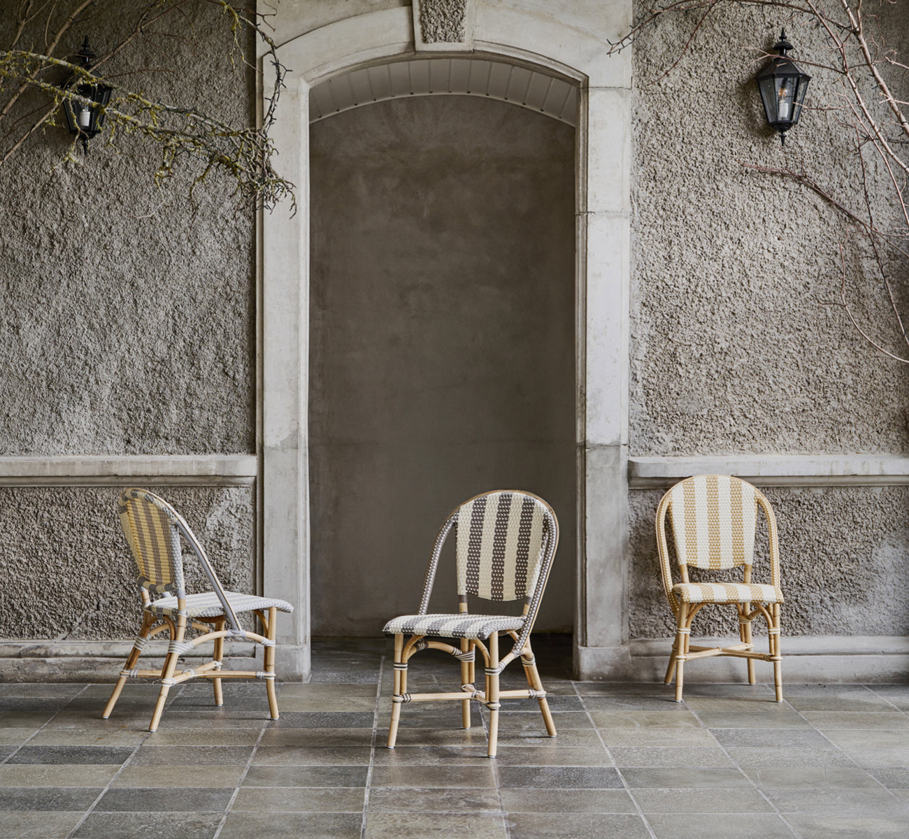 This is a lifestyle image of Sofie Dining Chair in striped grey ivory artfibre skin on rattan frame. Styled in a bright interior setting.