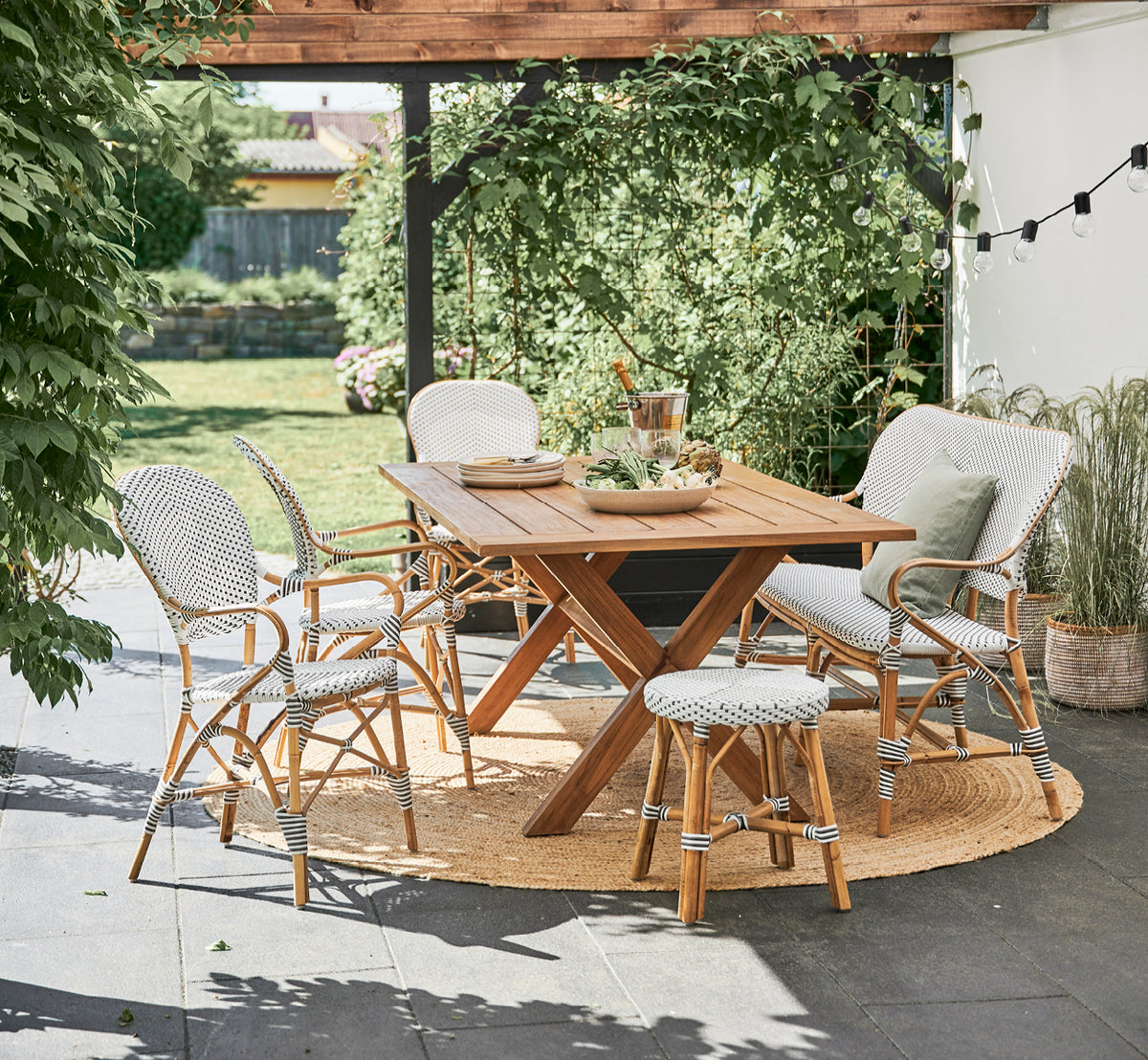This is a lifestyle image of Isabell Dining Armchair in white w cappuccino dot ArtFibre Skin on Rattan frame, in a bright dining area with large.