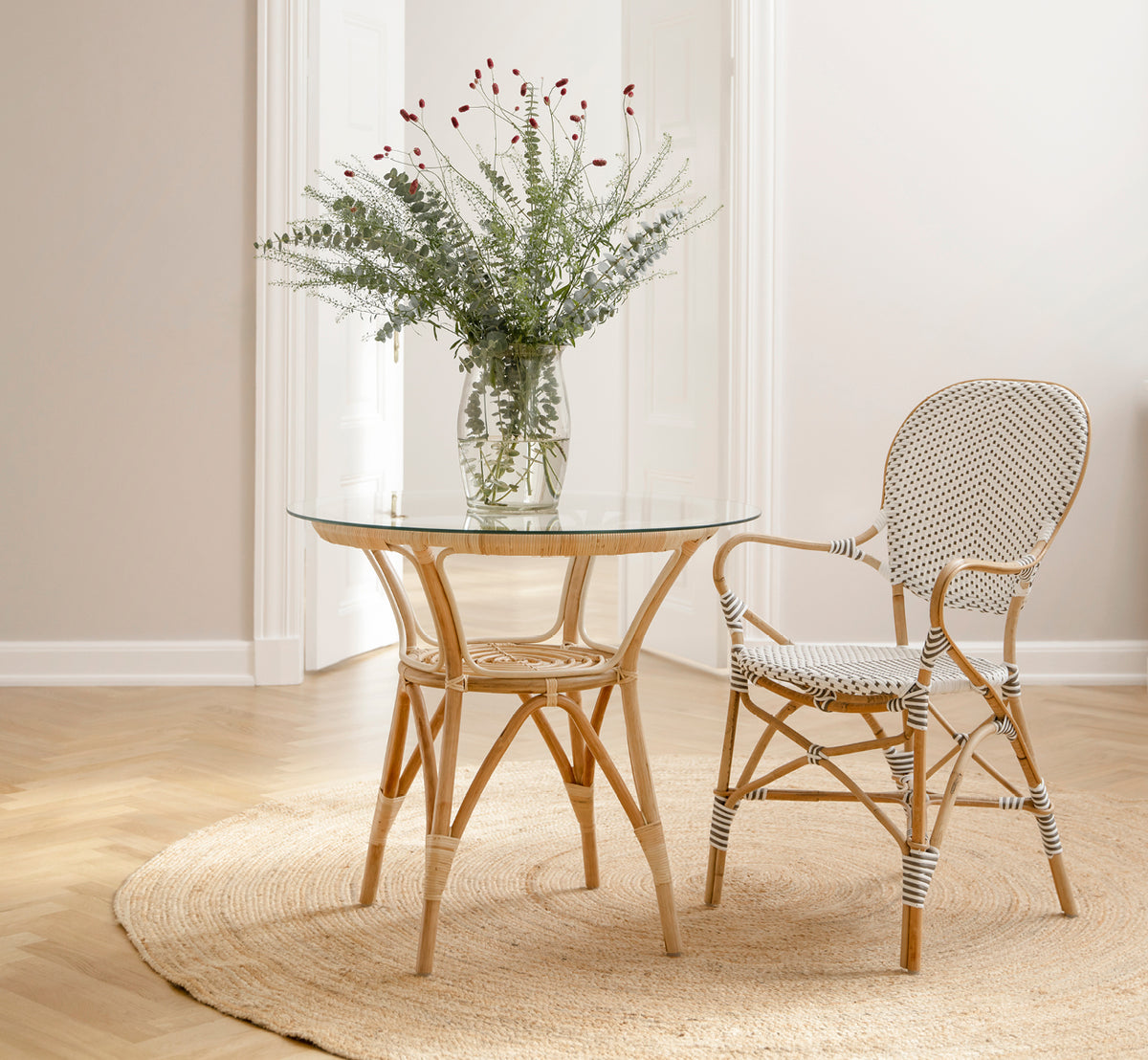 This is a lifestyle image of Isabell Dining Armchair in white w cappuccino dot ArtFibre Skin on Rattan frame, in a bright dining area with large.