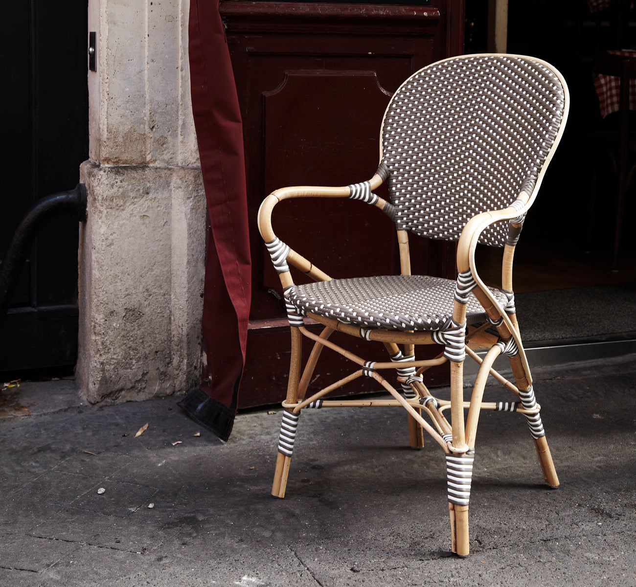 This is a lifestyle image of Isabell Dining Armchair in cappuccino w white dot ArtFibre skin on rattan frame, in a bright dining area with large.