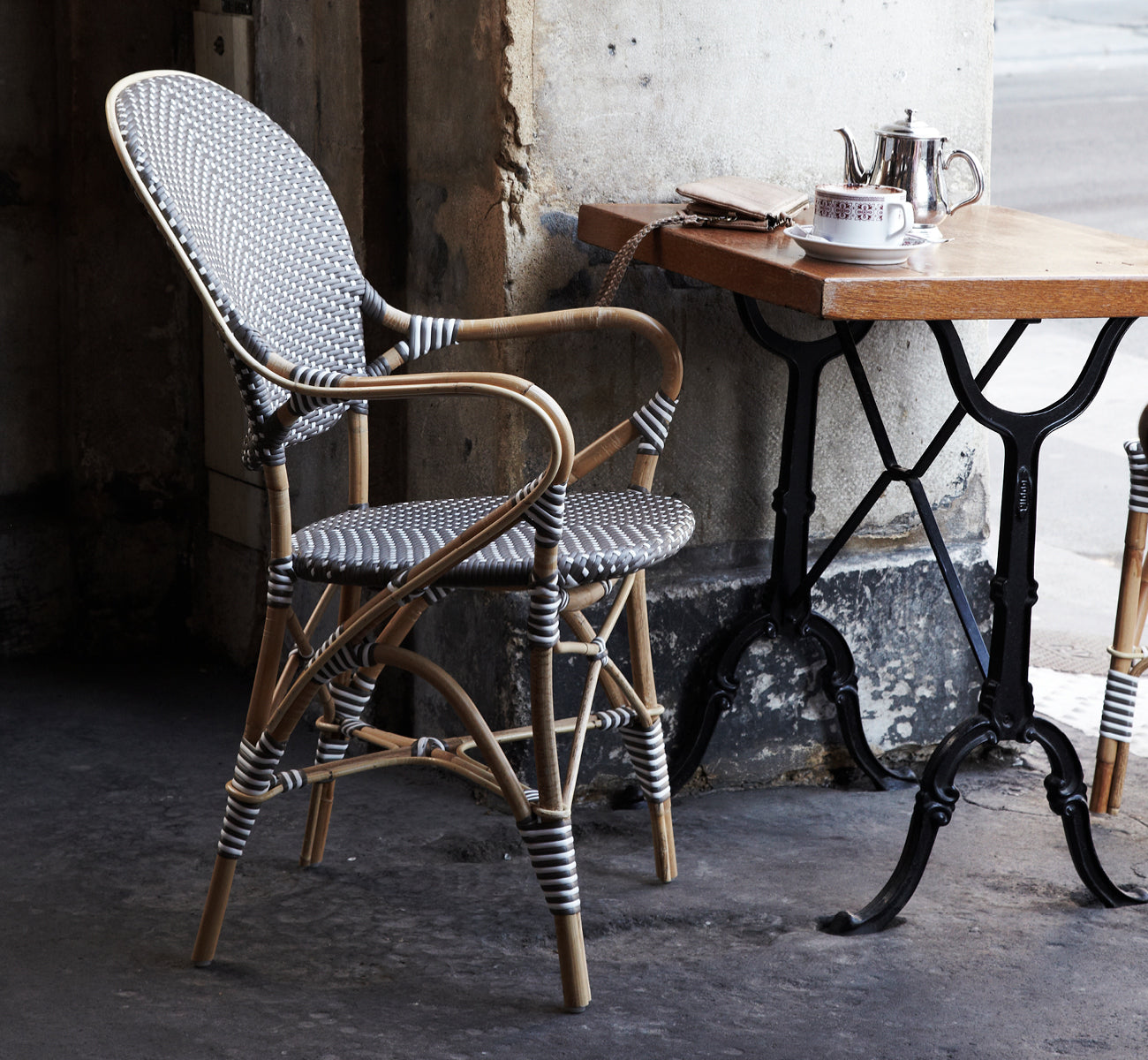 This is a lifestyle image of Isabell Dining Armchair in cappuccino w white dot ArtFibre skin on rattan frame, in a bright dining area with large.