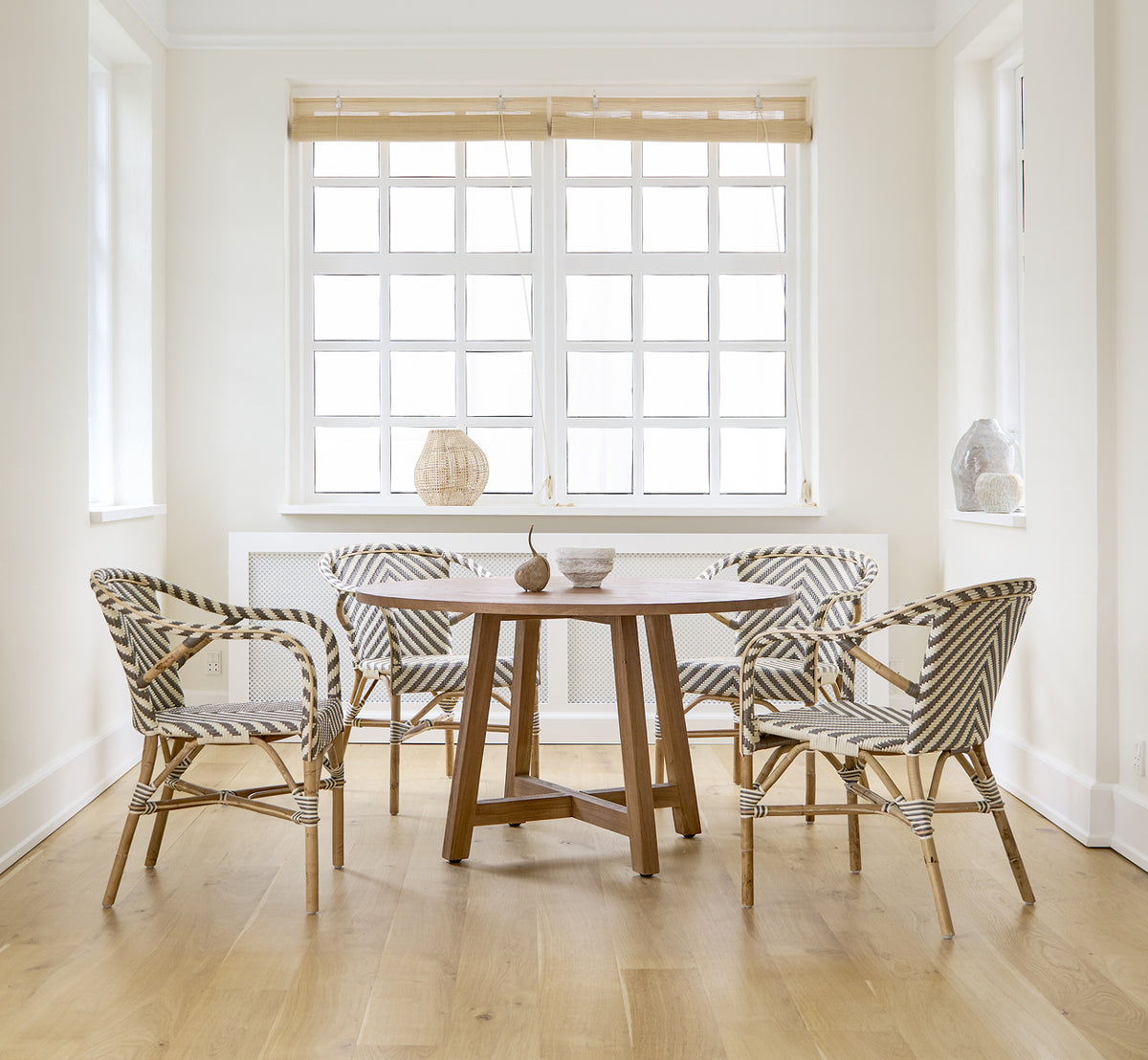 This is a lifestyle image of Madeleine Dining Chair in chevron cappuccino ivory ArtFibre skin on rattan frame. White dining room with oak floor.