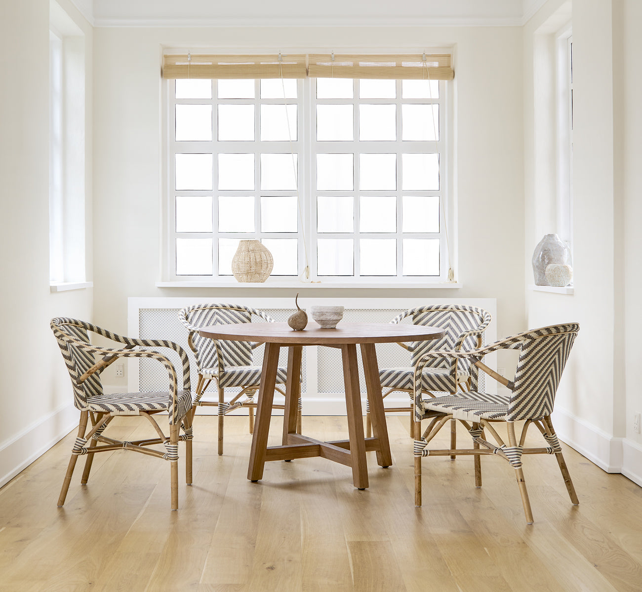 This is a lifestyle image of Madeleine Dining Chair in chevron cappuccino ivory ArtFibre skin on rattan frame. White dining room with oak floor.