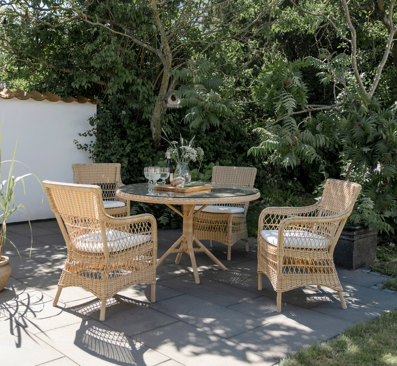 This is a lifestyle image of Marie Exterior Armchair in natural artfibre aluminium. Styled in a bright interior setting.
