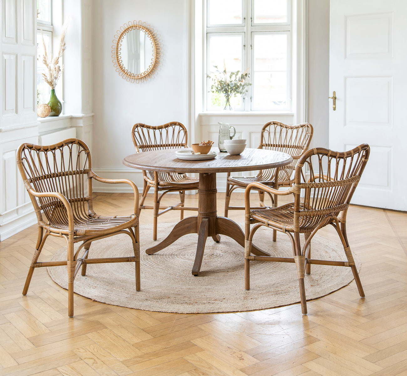 This is a lifestyle image of Michel Teak Dining Table in teak indoor. With Rossini chairs on a jute rug in a bright white loft.