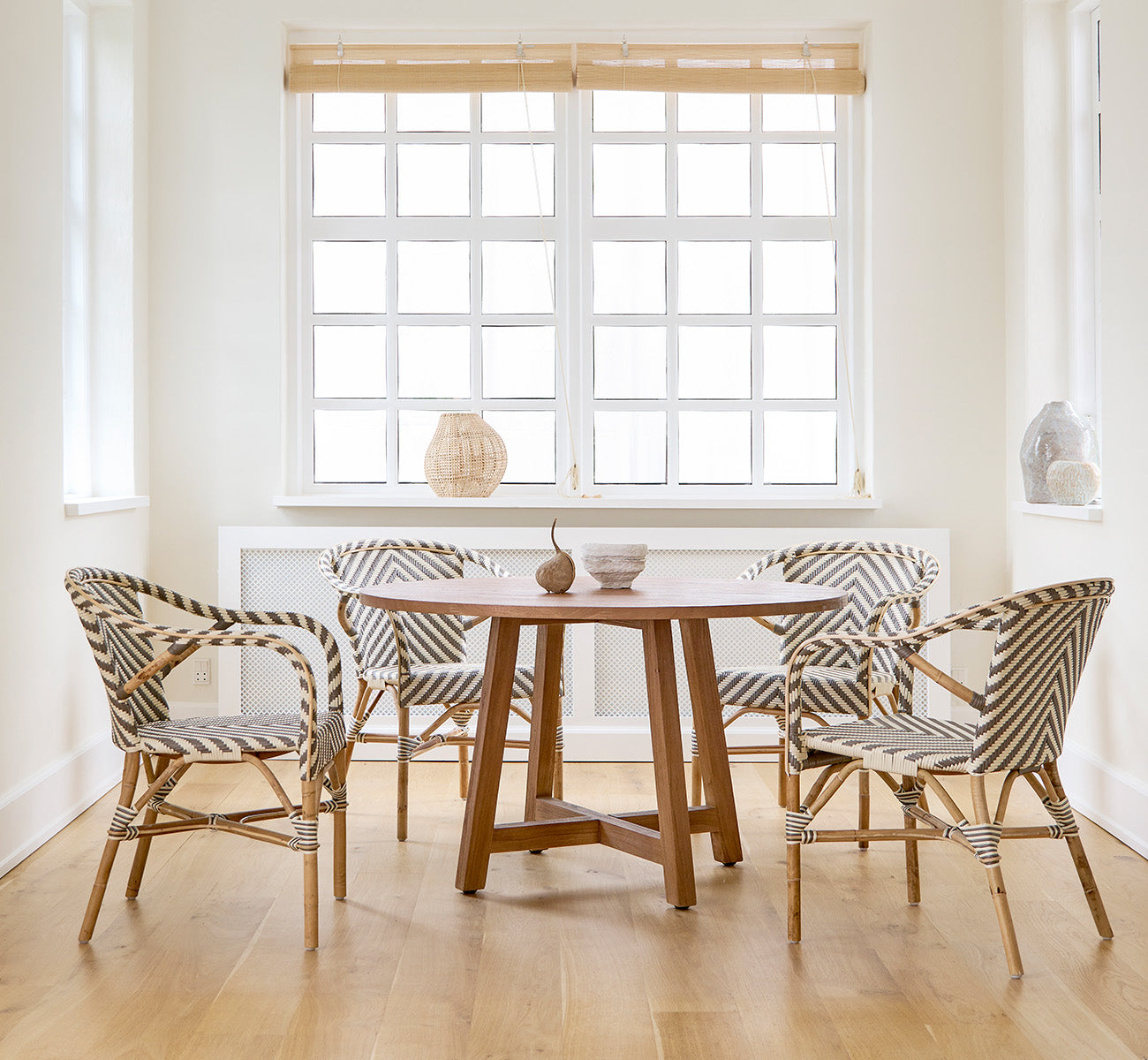 This is a lifestyle image of Aksel Dining Table in teak indoor, in a bright dining area with large windows and light wood flooring.