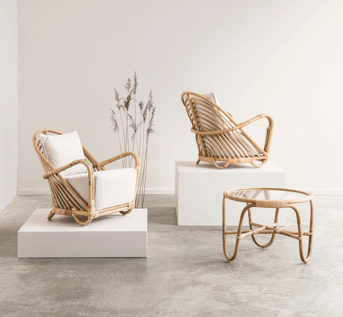 This is a lifestyle image of Charlottenborg Lounge Chair in polished Natural Rattan, in an elegant classical interior with ornate golden mouldings.