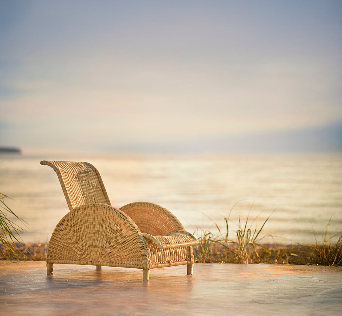 This is a lifestyle image of Paris Exterior Lounge Chair in natural core weave artfibre aluminium. Styled in a bright interior setting.