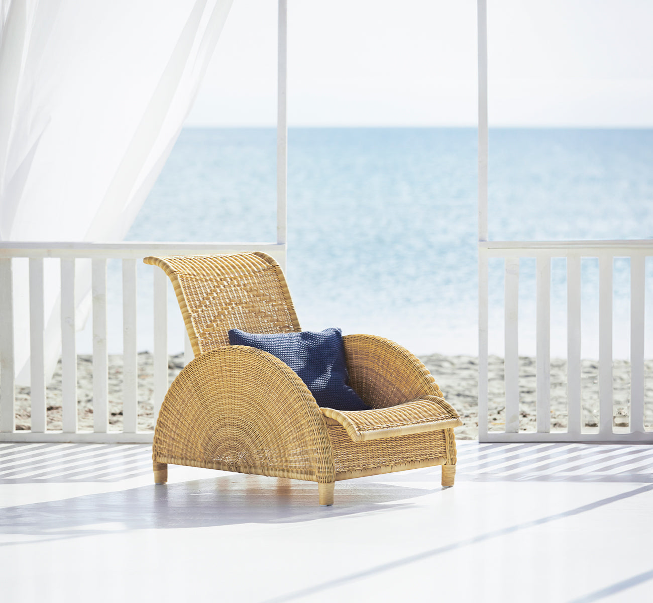 This is a lifestyle image of Paris Exterior Lounge Chair in natural core weave artfibre aluminium. Styled in a bright interior setting.