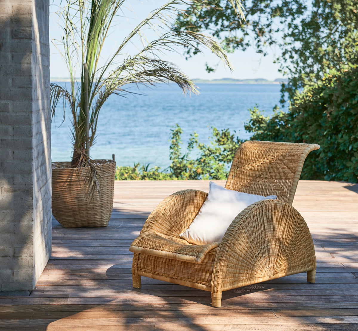 This is a lifestyle image of Paris Exterior Lounge Chair in natural core weave artfibre aluminium. Styled in a bright interior setting.