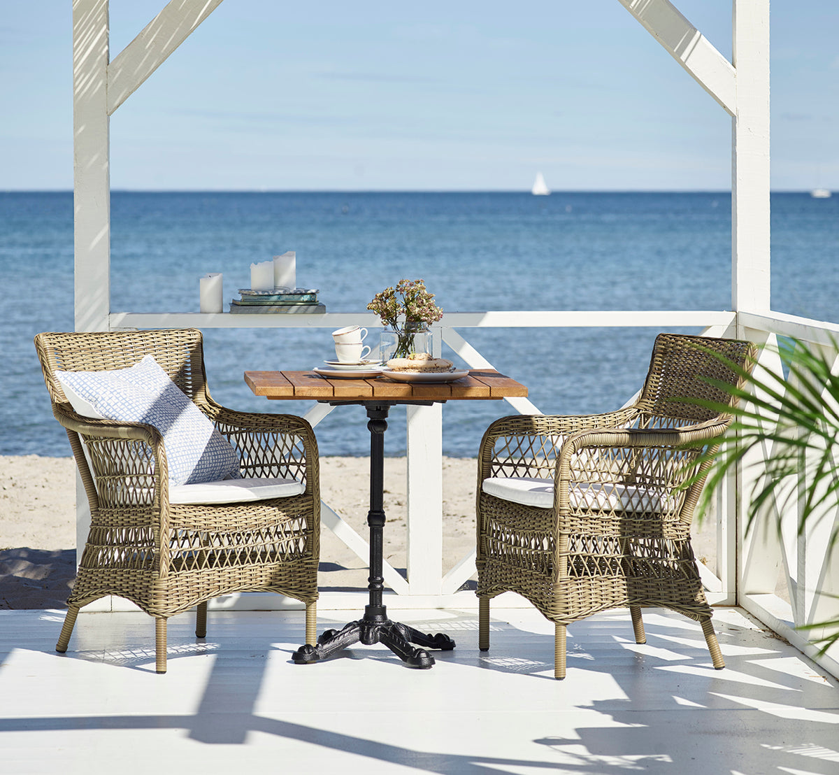 This is a lifestyle image of Lyon Bar Table | Teak 70x70 cm in cast iron. Styled in a bright interior setting.