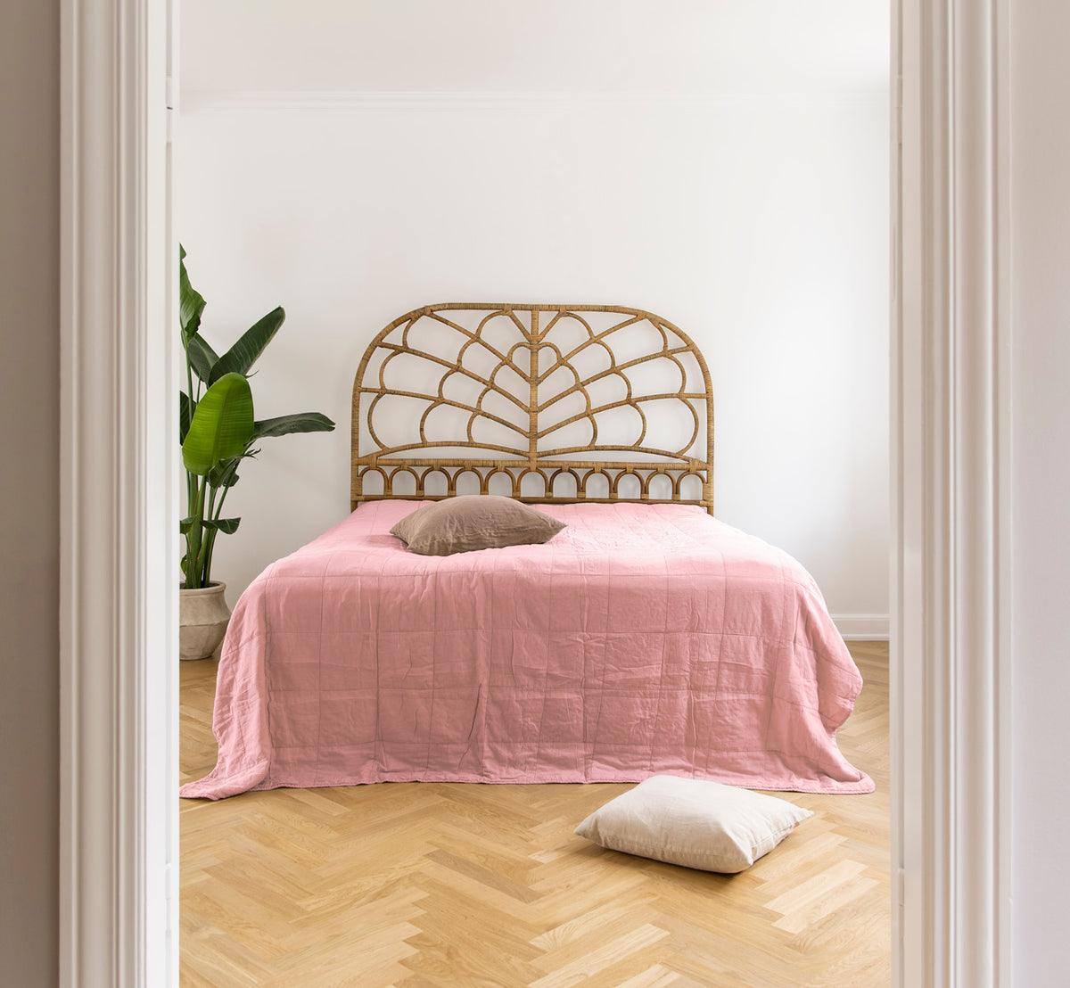 This is a lifestyle image of CTE058MR Bedspread in misty Rose Cotton, in a serene bedroom with neutral decor and herringbone parquet.