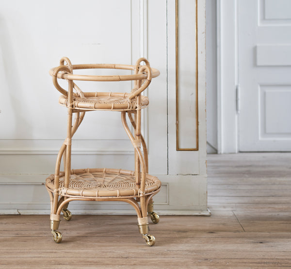 This is a lifestyle image of Fratellino Trolley in polished Natural Rattan, in a classical interior with ornate white panelled doors.