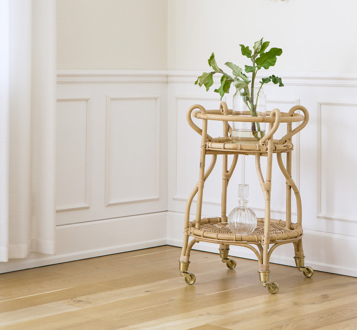 This is a lifestyle image of Fratellino Trolley in polished Natural Rattan, in a classical interior with ornate white panelled doors.