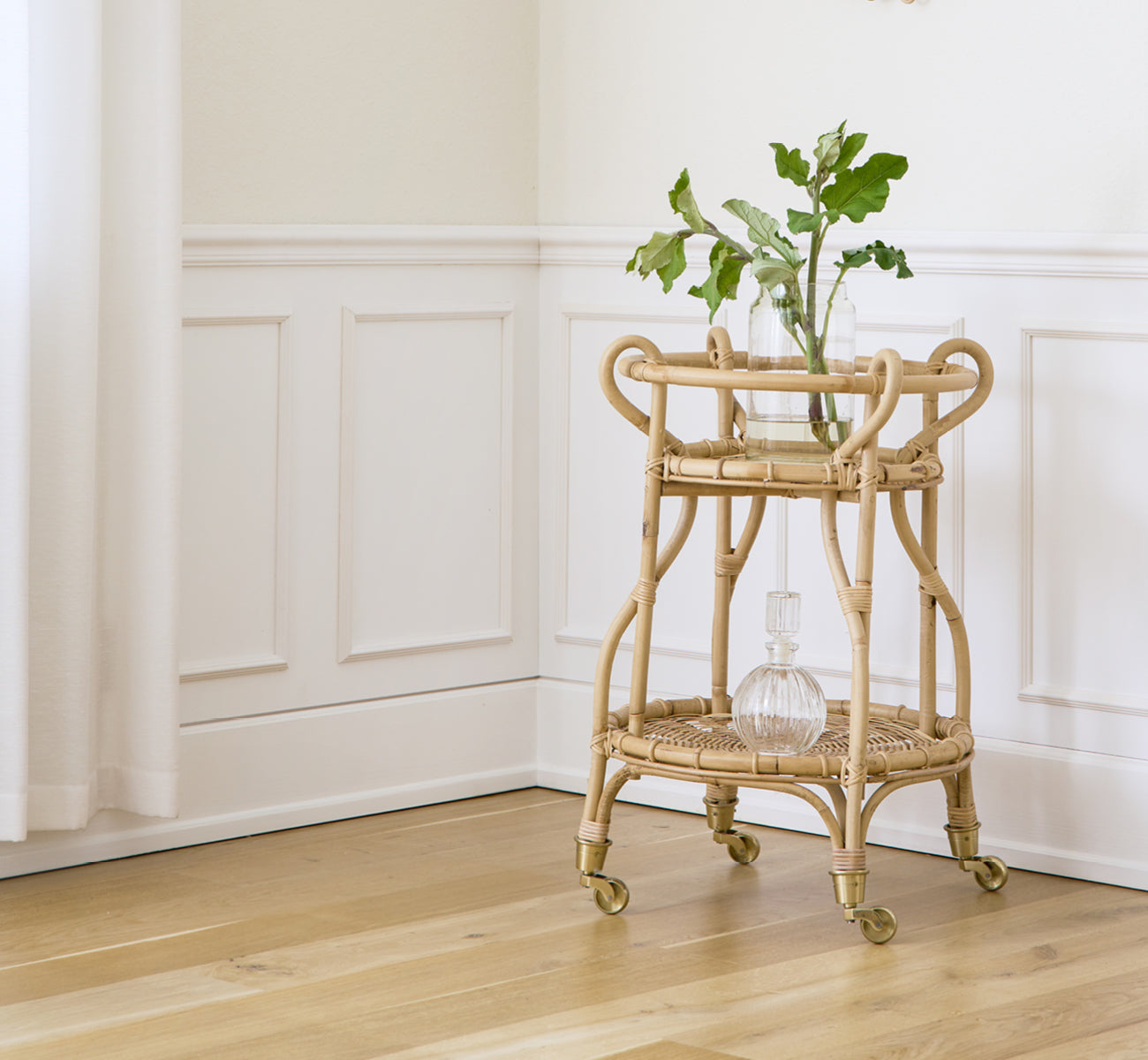 This is a lifestyle image of Fratellino Trolley in polished Natural Rattan, in a classical interior with ornate white panelled doors.