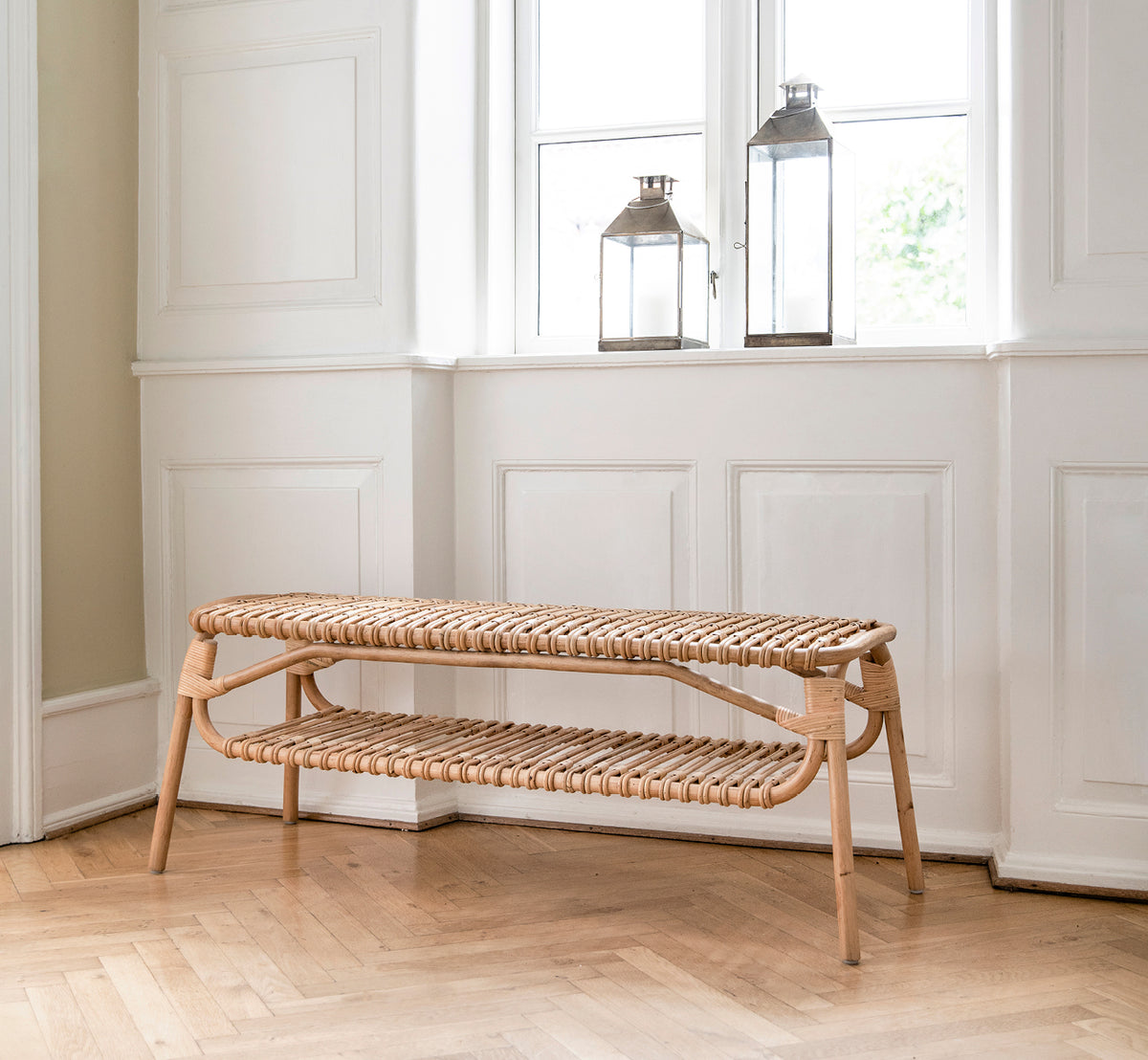 This is a lifestyle image of Machiya Bench in natural skin on rattan. Styled in a bright interior setting.