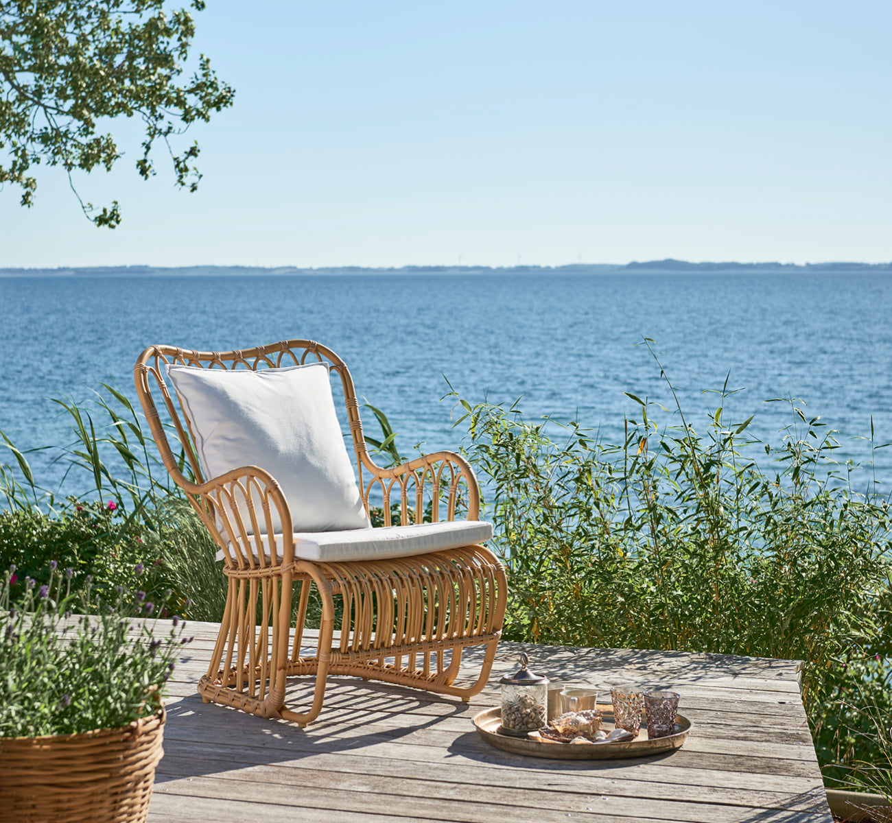 This is a lifestyle image of Tulip Exterior Lounge Chair in natural aluminium artfibre. Styled in a bright interior setting.