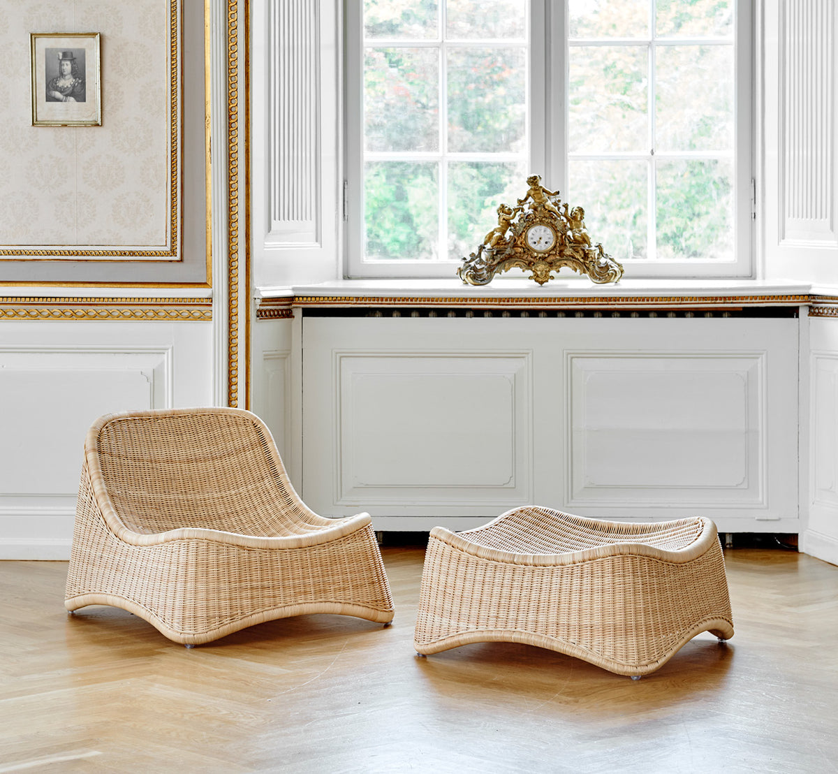 This is a lifestyle image of Chill Lounge Chair in natural core weave Rattan frame, in an elegant classical interior with ornate golden mouldings.
