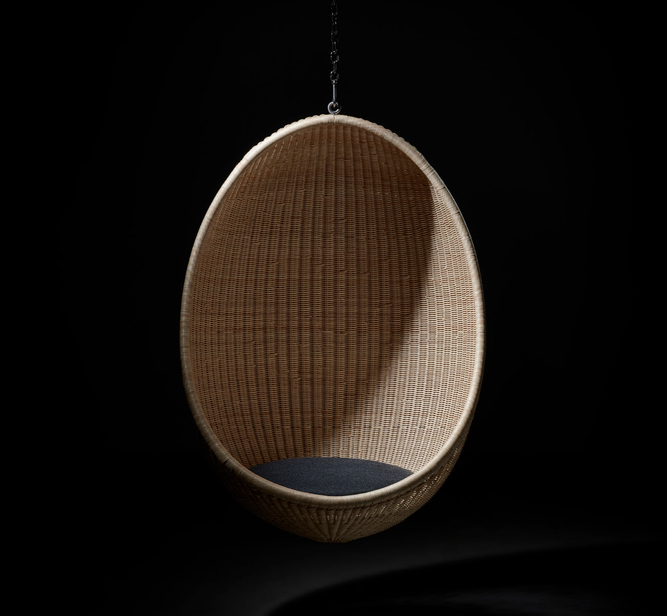 This is a lifestyle image of Hanging Egg Chair in natural core weave Rattan frame, in an elegant classical interior with ornate golden mouldings.