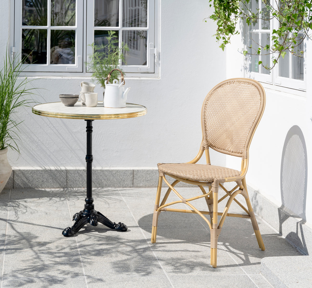 This is a lifestyle image of Rossini Exterior Dining Chair in natural aluminium artfibre. Styled in a bright interior setting.
