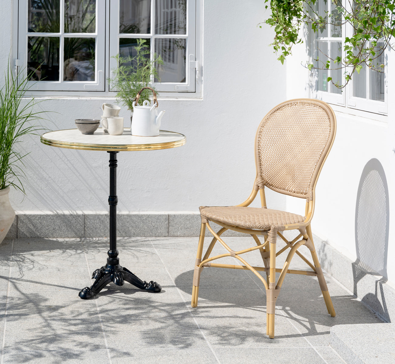 This is a lifestyle image of Rossini Exterior Dining Chair in natural aluminium artfibre. Styled in a bright interior setting.