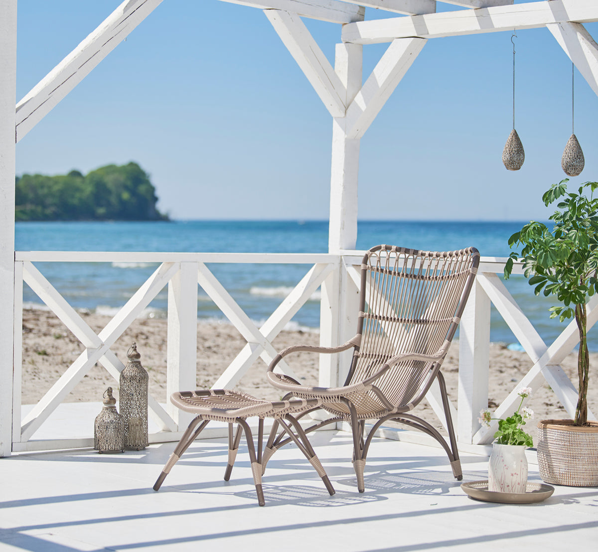 This is a lifestyle image of Monet Exterior Lounge Chair in moccaccino aluminium artfibre. Styled in a bright interior setting.