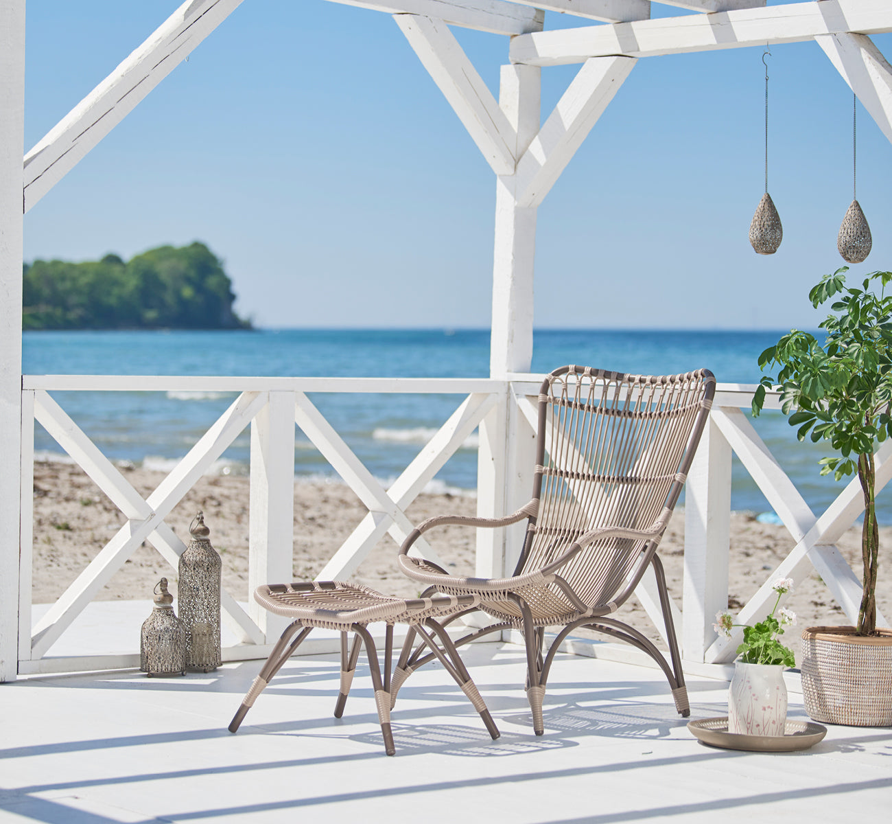 This is a lifestyle image of Monet Exterior Lounge Chair in moccaccino aluminium artfibre. Styled in a bright interior setting.