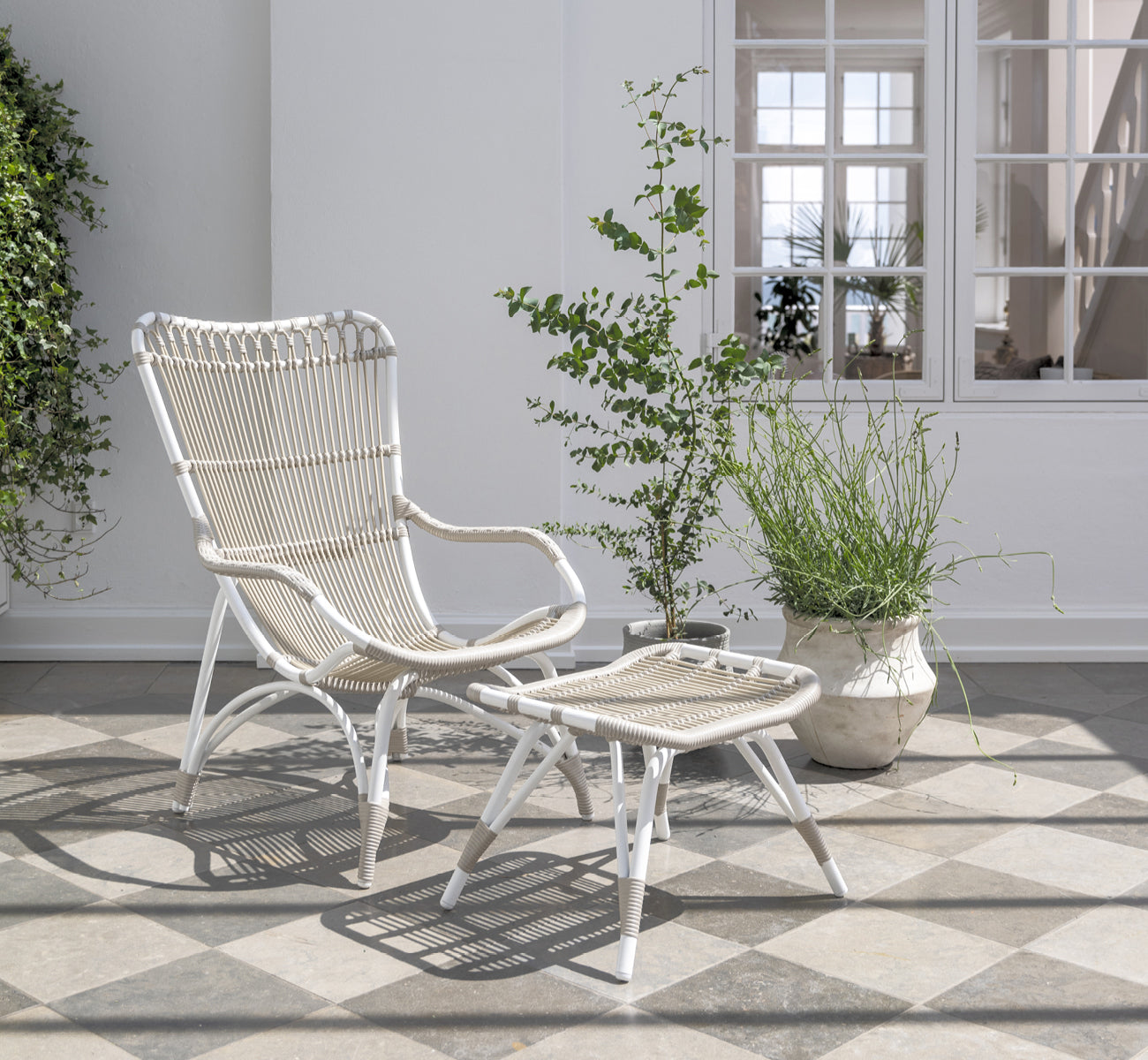 This is a lifestyle image of Monet Exterior Footstool in dove white aluminium artfibre. On a beach porch with lounge chair.